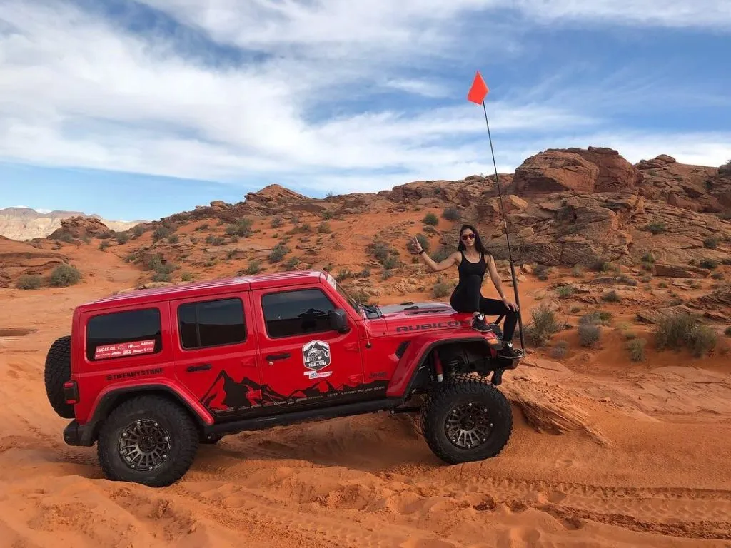 Tiffany Stone Trail to SEMA Tiffany sitting on the hood giving peace sign